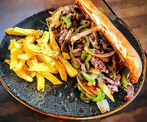 English Menu 11 Thinly sliced ribeye steak, grilled to perfection with onions, green bell peppers and melted cheese. All this cheesy goodness is piled high on a soft, authentic hoagie roll, flown in straight from Philly!